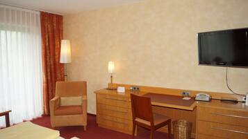 Ein Hotelzimmer mit einem Bett, einem Schreibtisch mit Stuhl, einem Fernseher und einer Lampe.