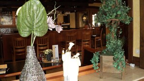 A restaurant interior with wooden furniture, a bar area, and decorative plants. - Hotel an der Ilse (Lemgo)