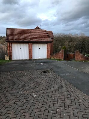 A two-story building with a red-tiled roof and two white garage doors. - 3 Bedroom Holiday Home With River Views (Frodsham)