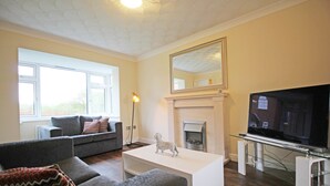 A living room with a sofa, a coffee table, a fireplace, and a television. - 3 Bedroom Holiday Home With River Views (Frodsham)