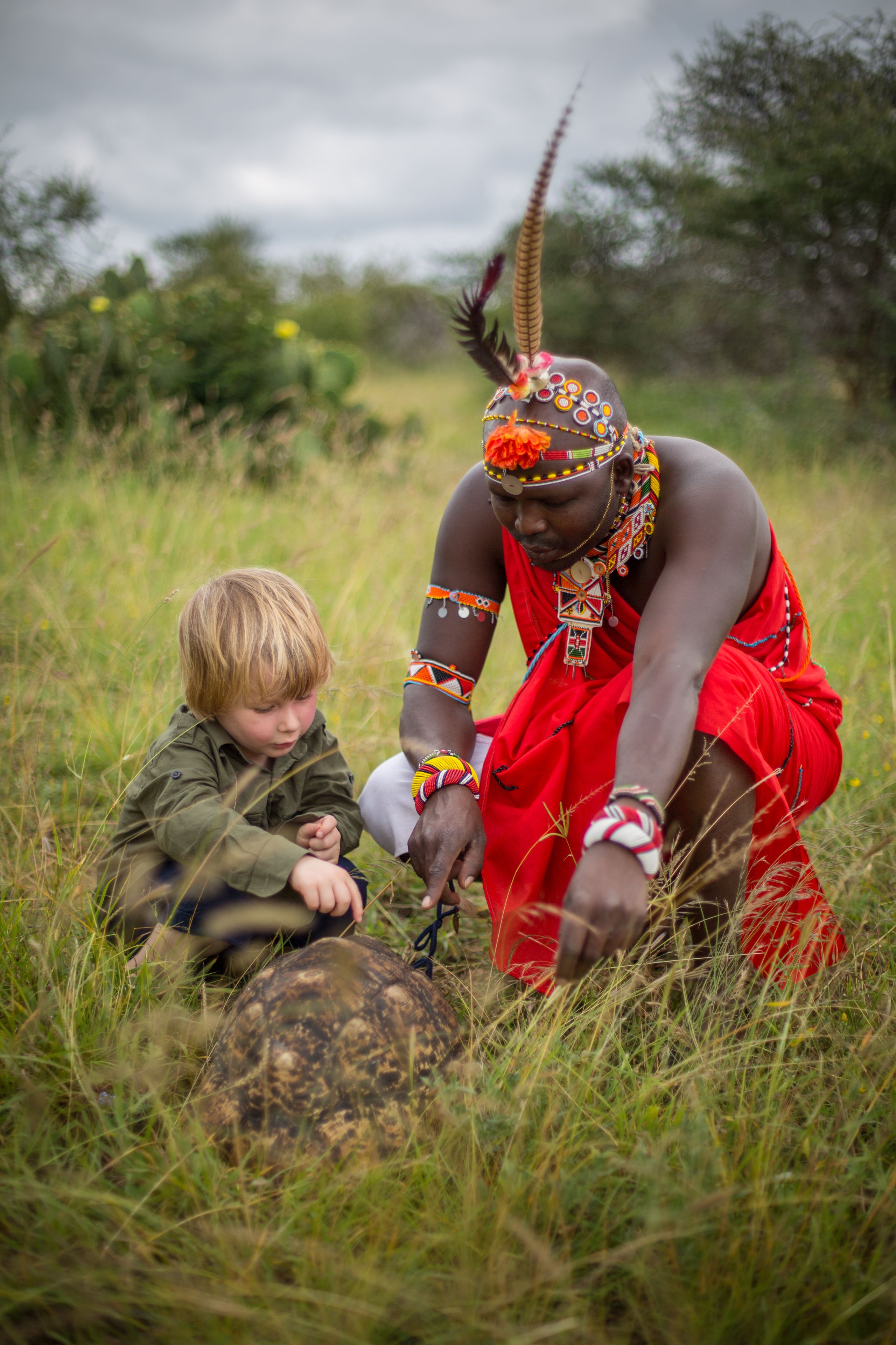 A person in traditional attire sitting in a grassy field.
