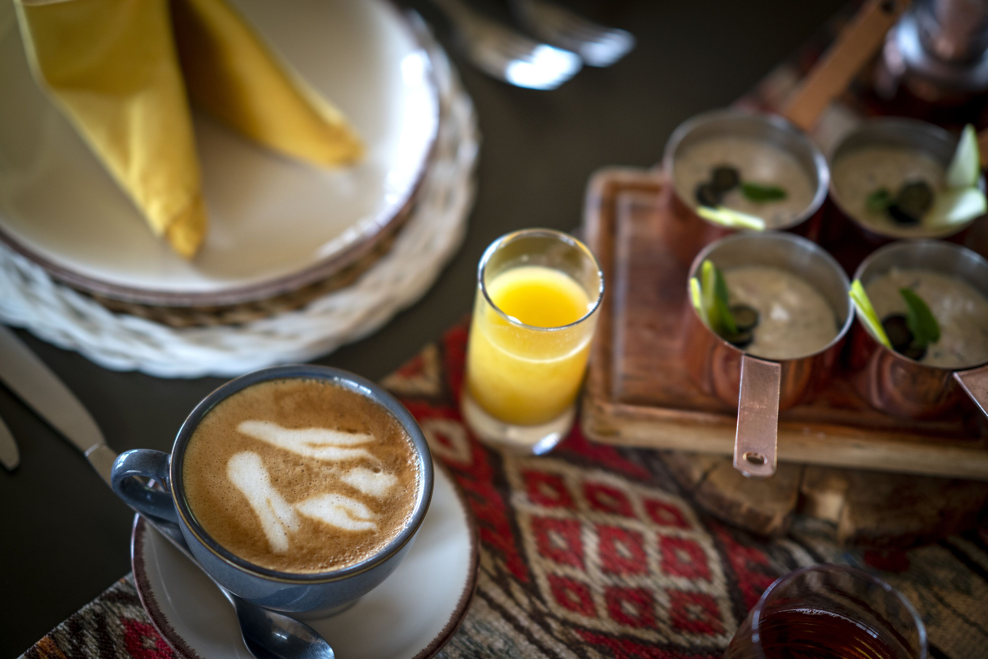 Une table avec une tasse de café, un verre de jus d’orange et plusieurs petits bols contenant différents aliments.