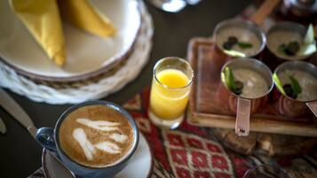 Une table avec une tasse de café, un verre de jus d’orange et plusieurs petits bols contenant différents aliments.
