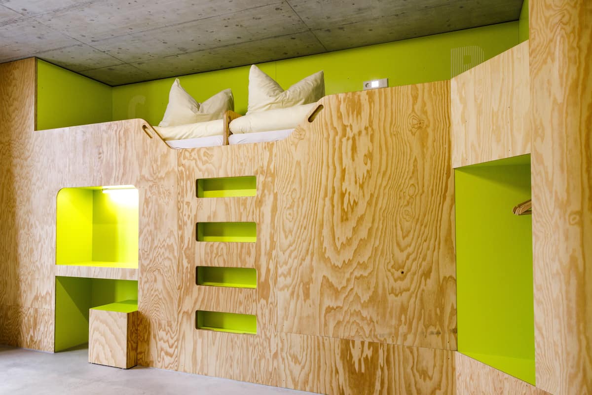 Een kamer met een stapelbed, een klein bureau en een groene accentmuur.