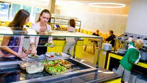 Zona de buffet con diferentes opciones de comida y un mostrador donde el personal está atendiendo.