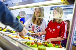 Een buffet met diverse soorten eten en een persoon die serveert.