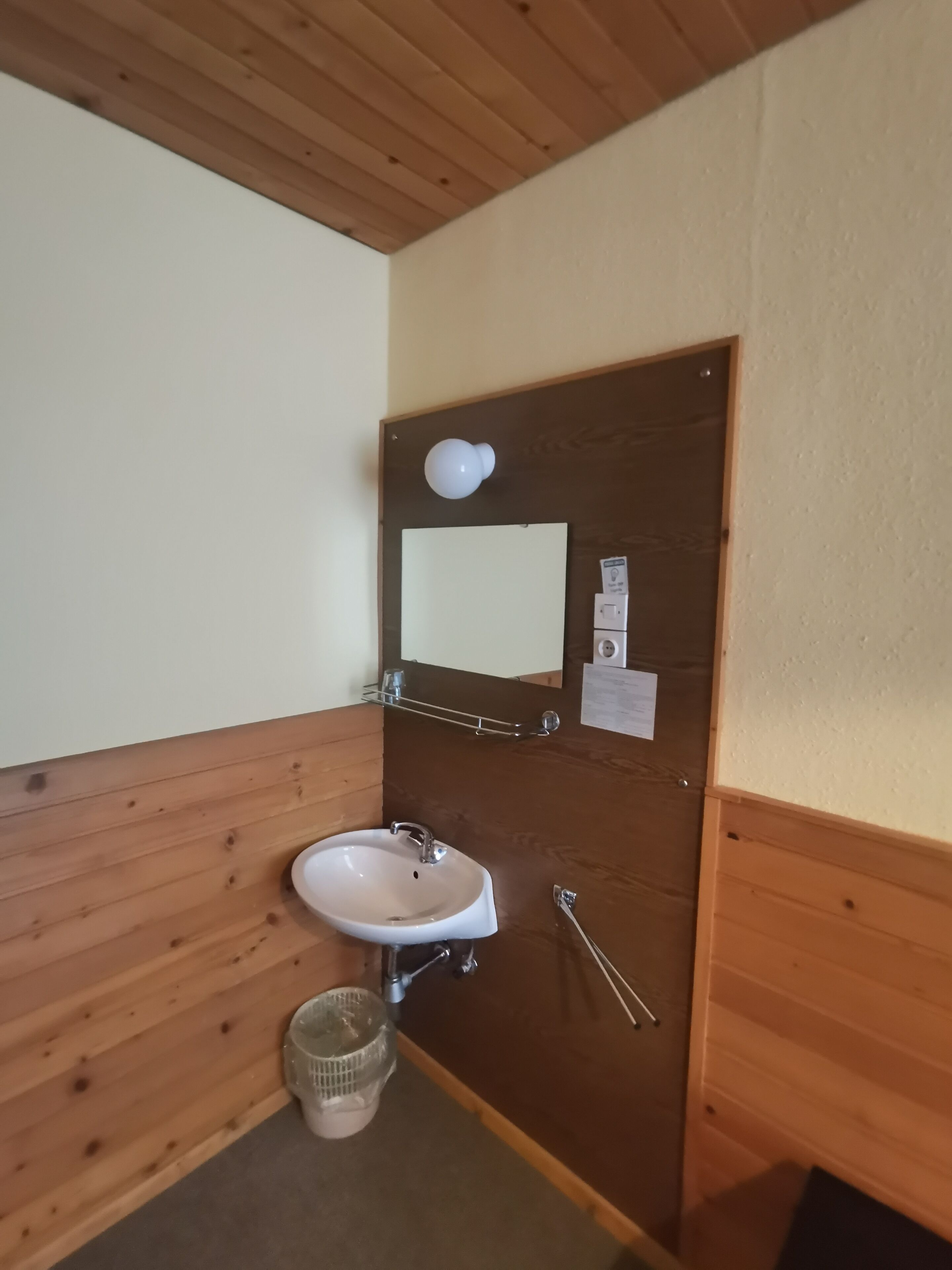 A small bathroom with a wooden vanity, a sink, a mirror, and a towel rack.
