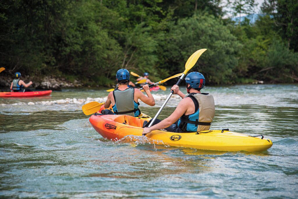People kayaking on a river surrounded by trees.