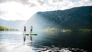 Two people paddleboarding on a calm lake with mountains in the background.