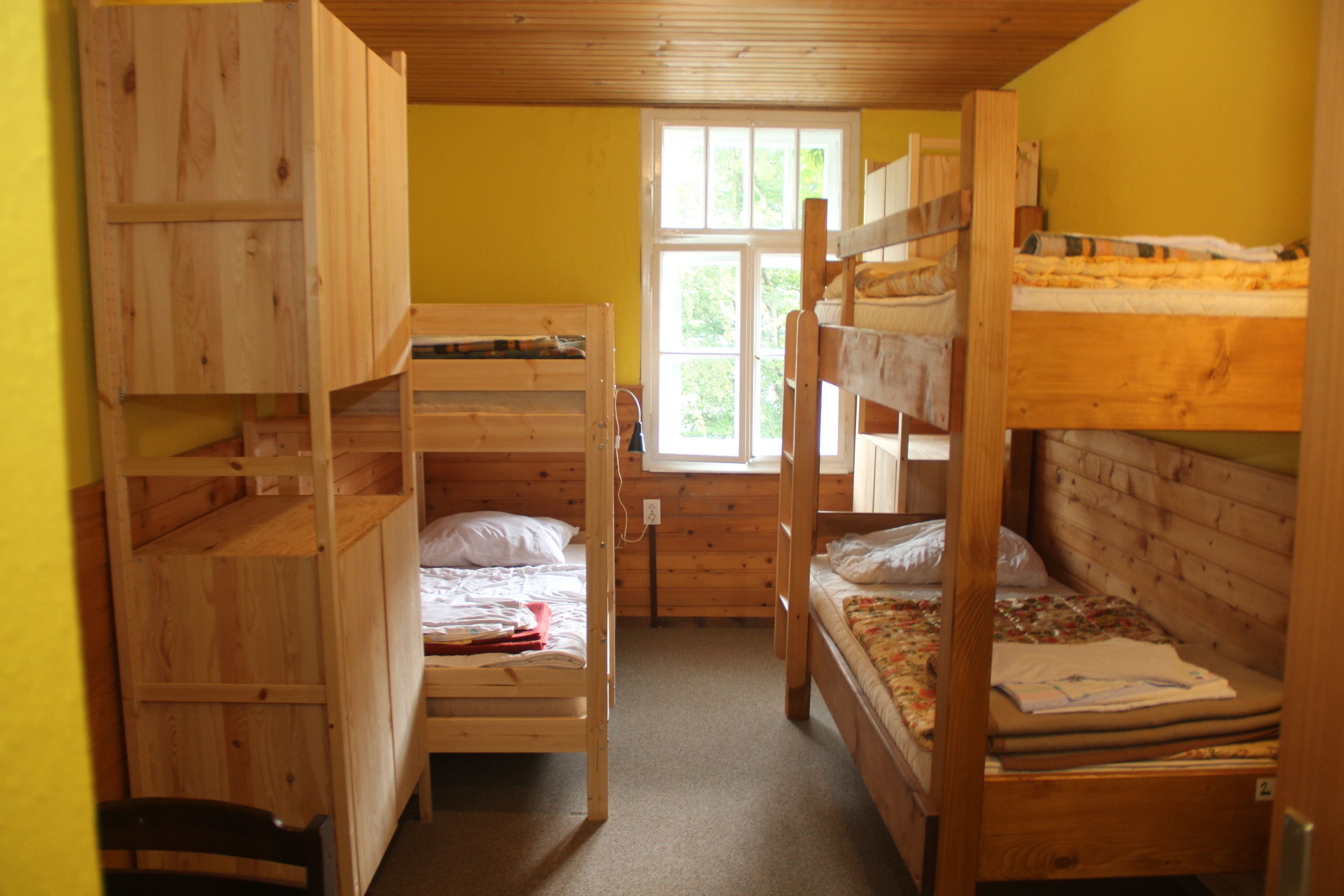 Une chambre avec un lit superposé, des murs en bois et une fenêtre.