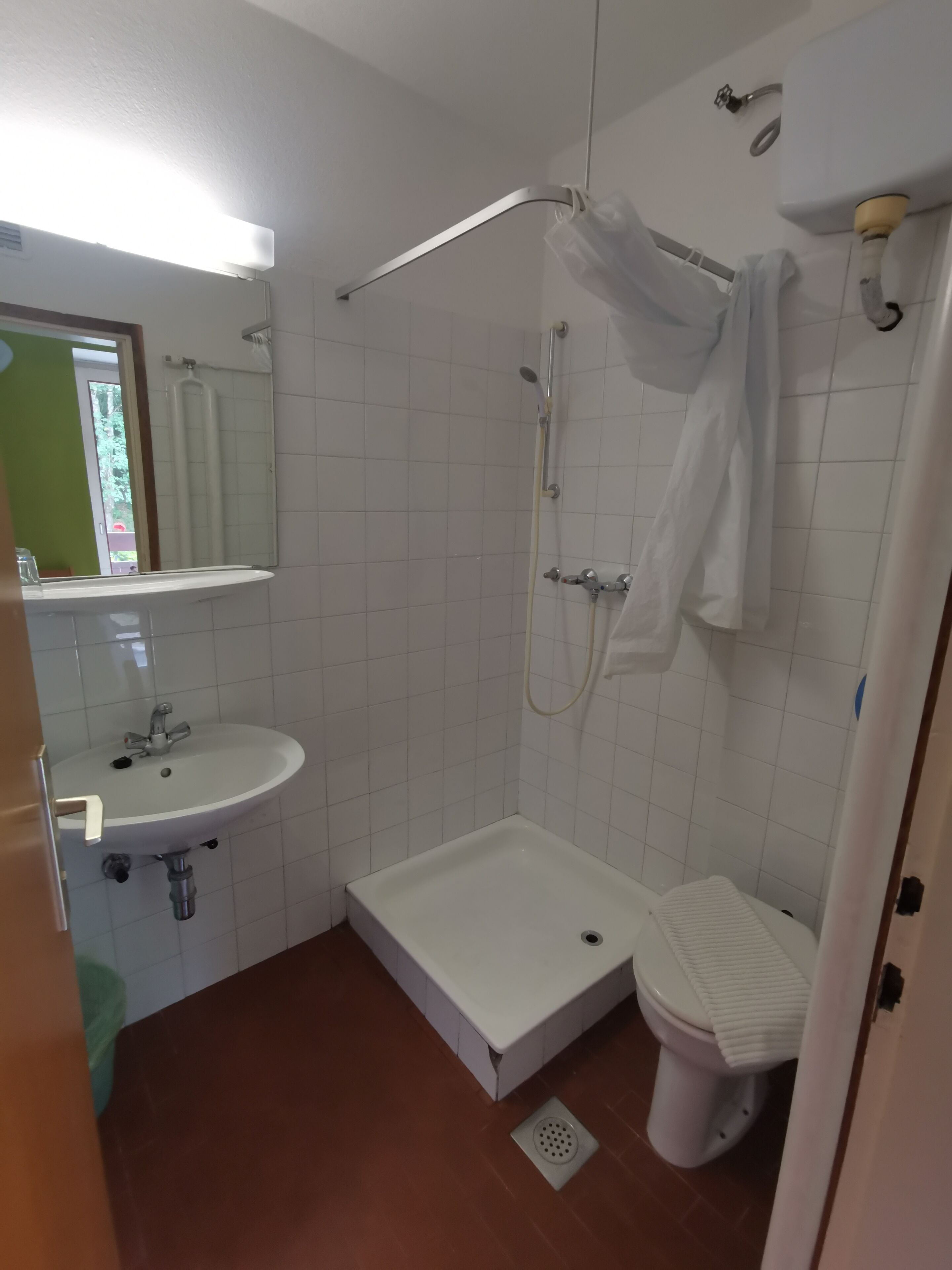 A small, clean bathroom with a white sink, a toilet, and a shower area.