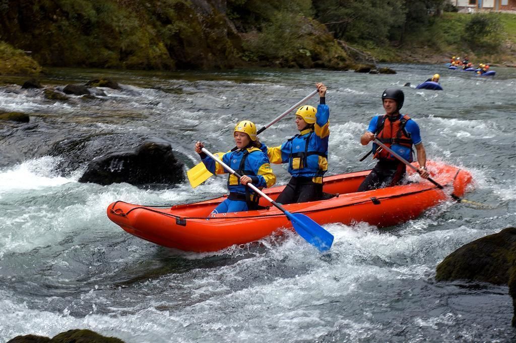 Un grupo de personas en una balsa roja navegando un río con rápidos.