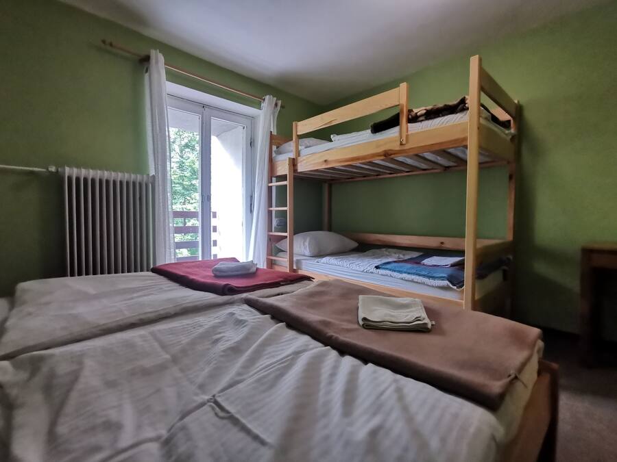 Ein Schlafraum mit Etagenbetten, einem Fenster und einem ordentlich bezogenen Bett.