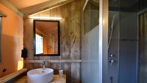 Un baño de madera con un espejo grande, un lavamanos y una ducha con cerramiento de vidrio.