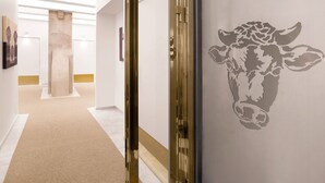 A hallway with a modern design, featuring a glass door with a golden frame, a beige carpet, and a wall with a cow silhouette. - Hotell Västmannagatan no.61 (Stockholm)