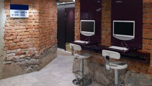 Un baño con pared de ladrillo, dos lavamanos y un cartel con números de habitaciones.