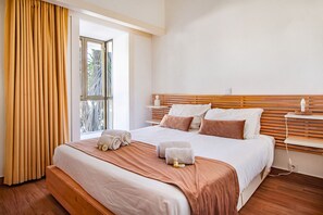 A hotel room with a large bed, wooden headboard, and a window with curtains. - Casa Moura Golfe | 3 Bedrooms | Vilamoura (Vilamoura)