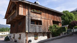 Un edificio rústico de madera con base de piedra, balcones con jardineras y un letrero que indica un restaurante.