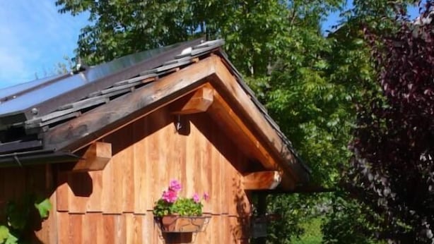 Una cabaña de madera con una mesa lista para cenar, rodeada de follaje.