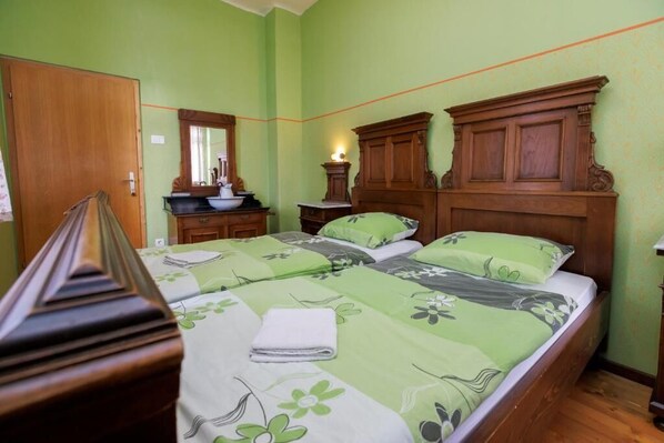 Un dormitorio con cama de madera, paredes verdes y cómoda de madera con espejo.