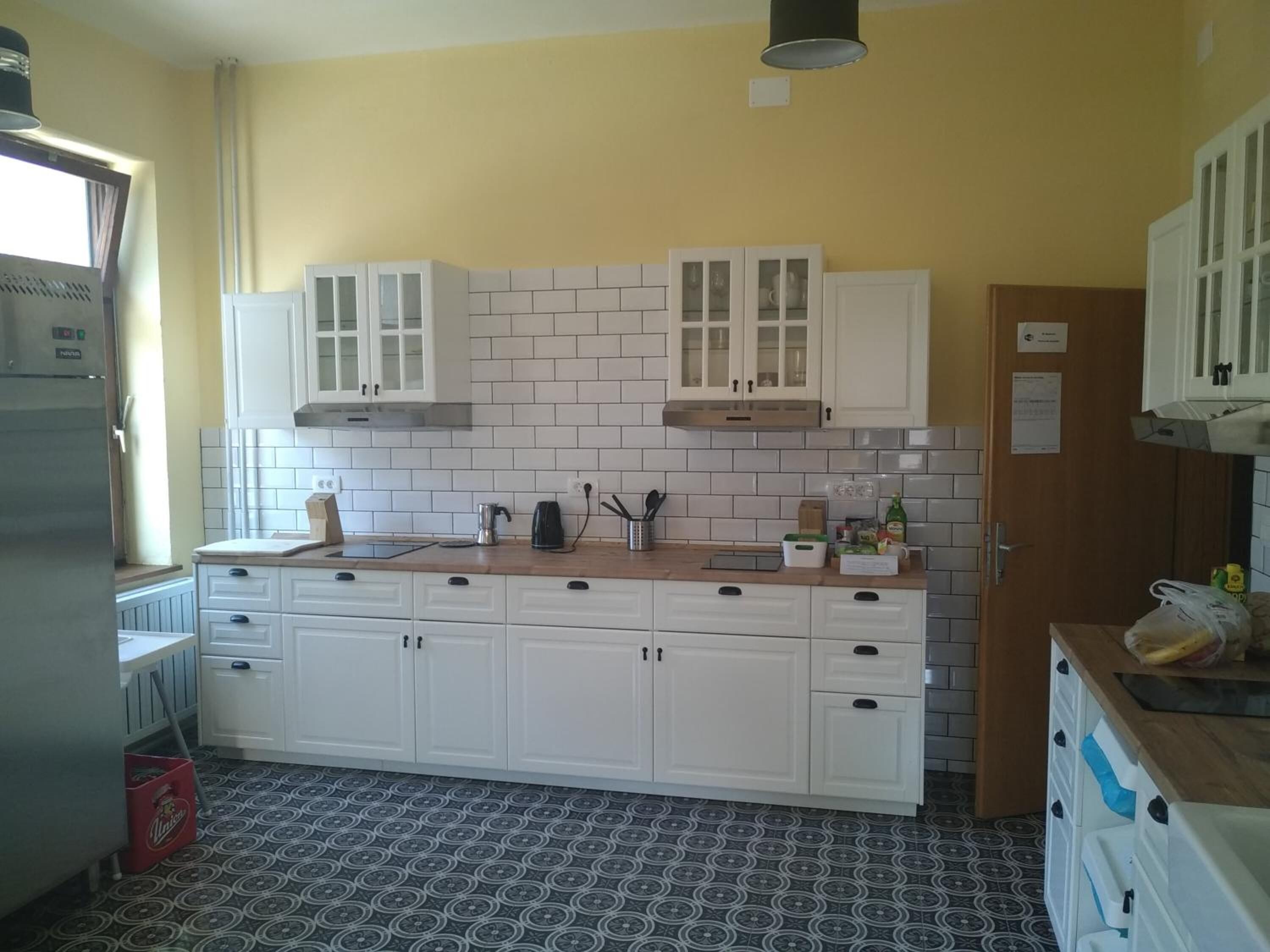 Una cocina con armarios blancos, salpicadero de azulejos y suelo estampado.