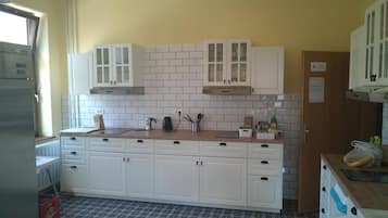 Una cocina con armarios blancos, salpicadero de azulejos y suelo estampado.