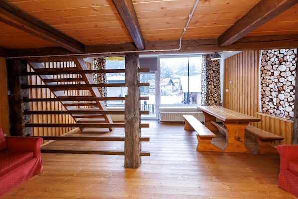 Interior de madera con una escalera, bancos y vistas al exterior.
