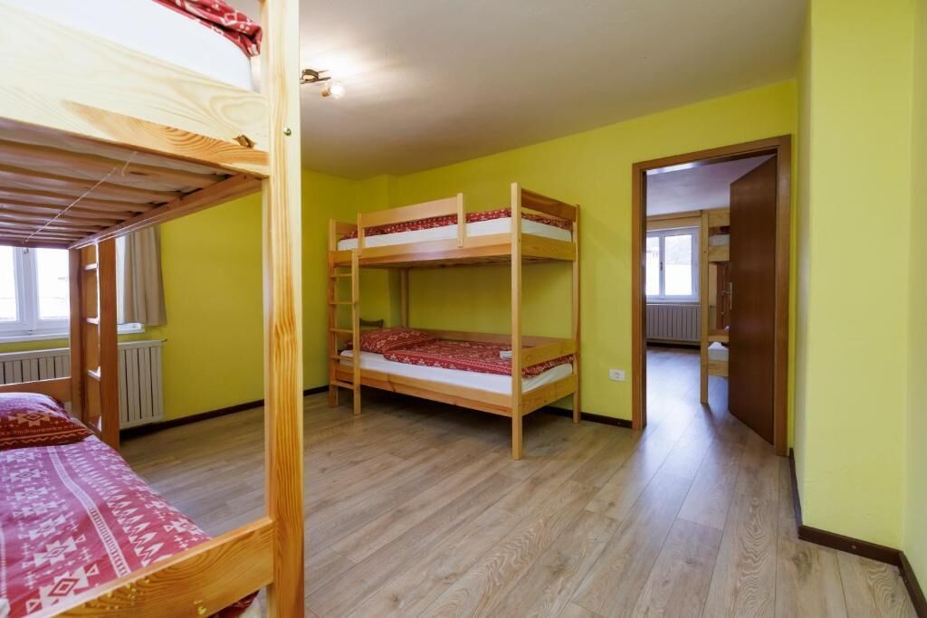 A room with two bunk beds, a radiator, and a door leading to another room.