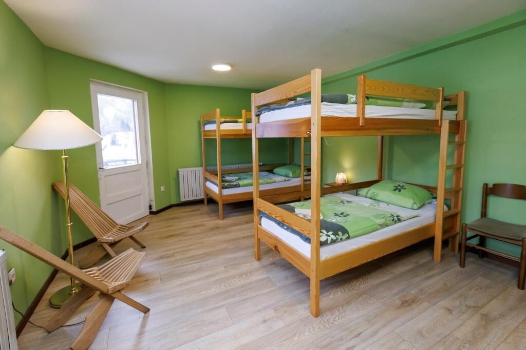 Una habitación con dos literas, una silla, una lámpara y un radiador.