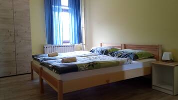 Un dormitorio con una cama de madera, una mesita de noche, un armario y una ventana con cortinas azules.