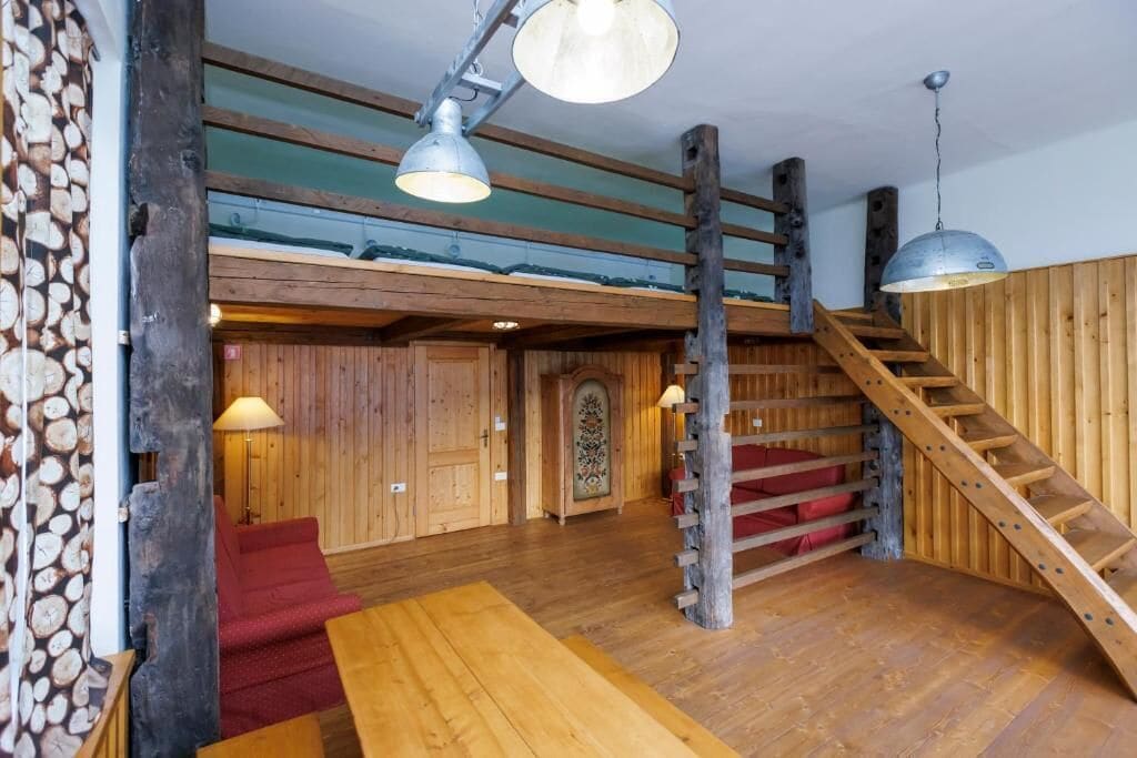 A wooden interior with a staircase, a red sofa, and a wooden table.