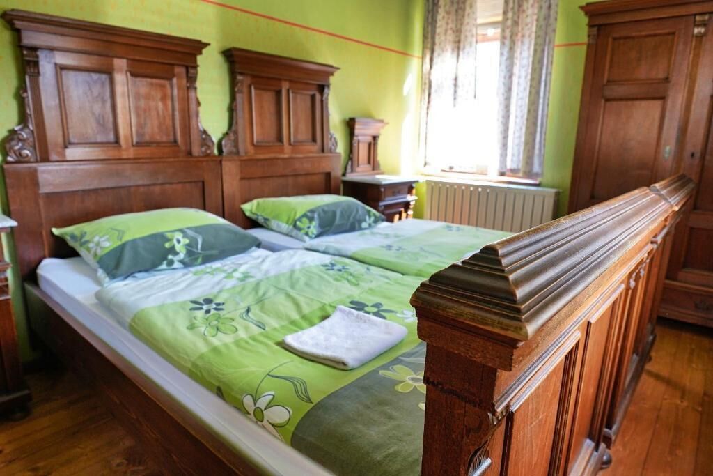 Un lit double avec une tête de lit en bois et une literie à motifs floraux verts.