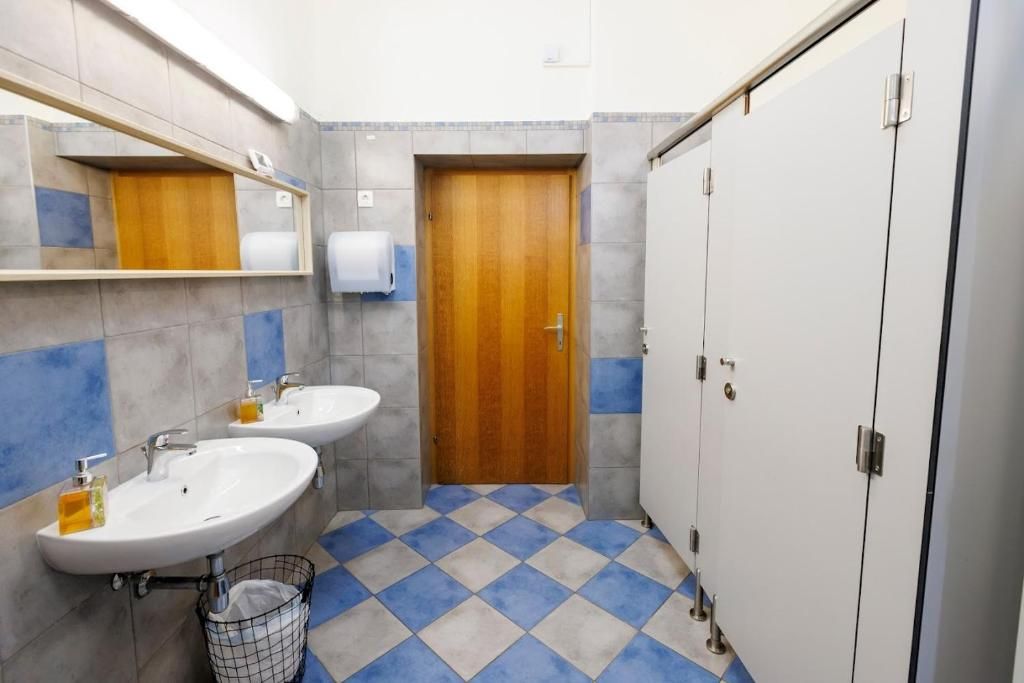 Un baño con dos lavamanos, una puerta de madera y suelo de baldosas.