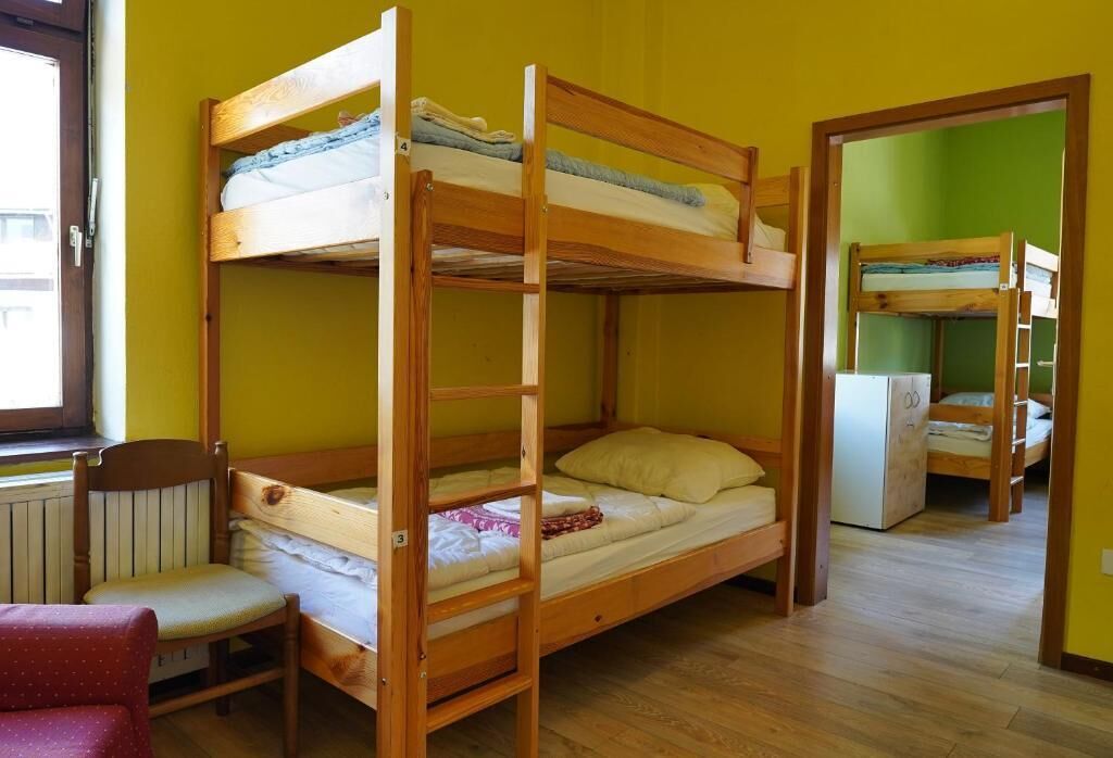 A bunk bed room with a chair and a radiator.