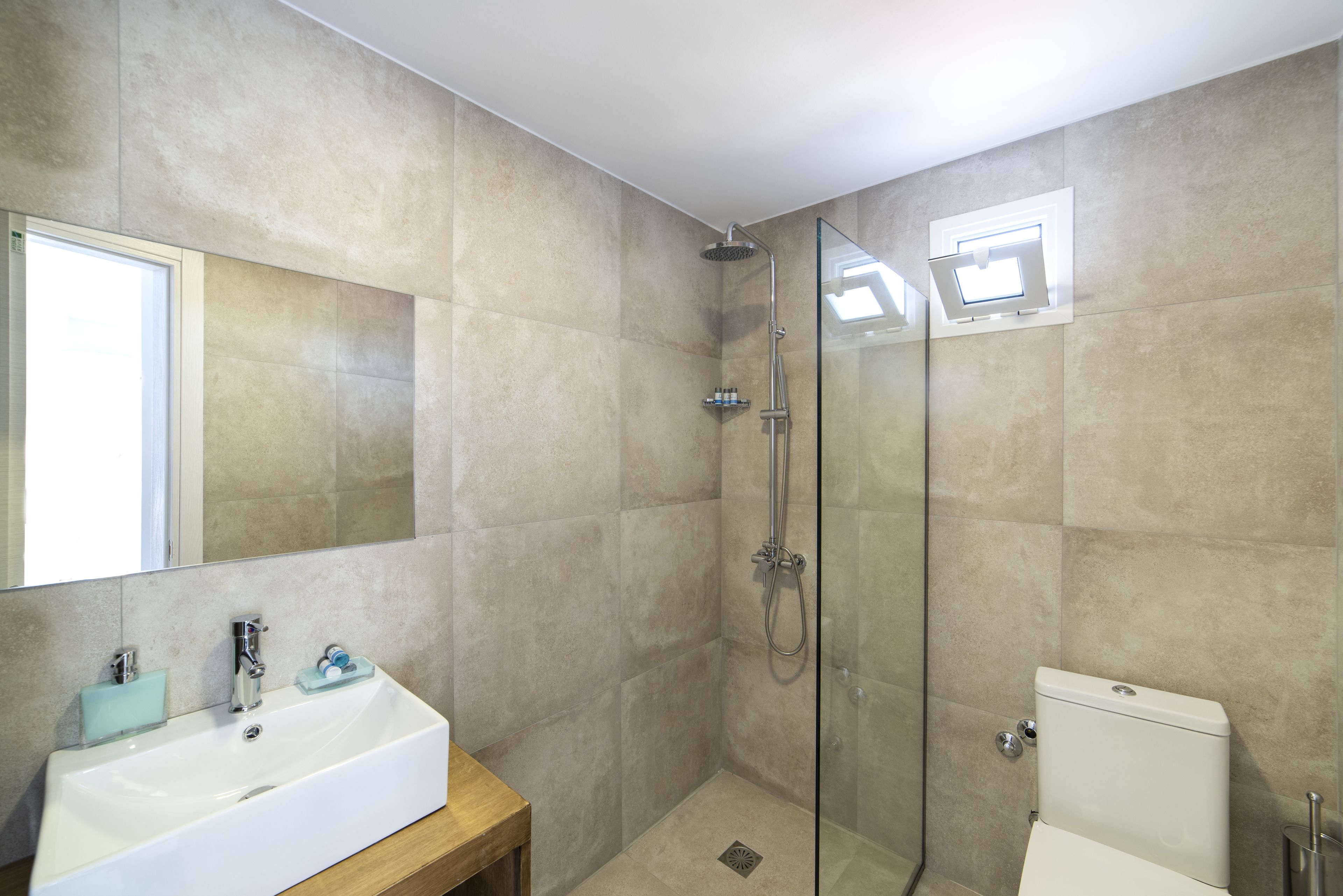 Een badkamer met een douchecabine van glas, een witte wastafel en een toilet.