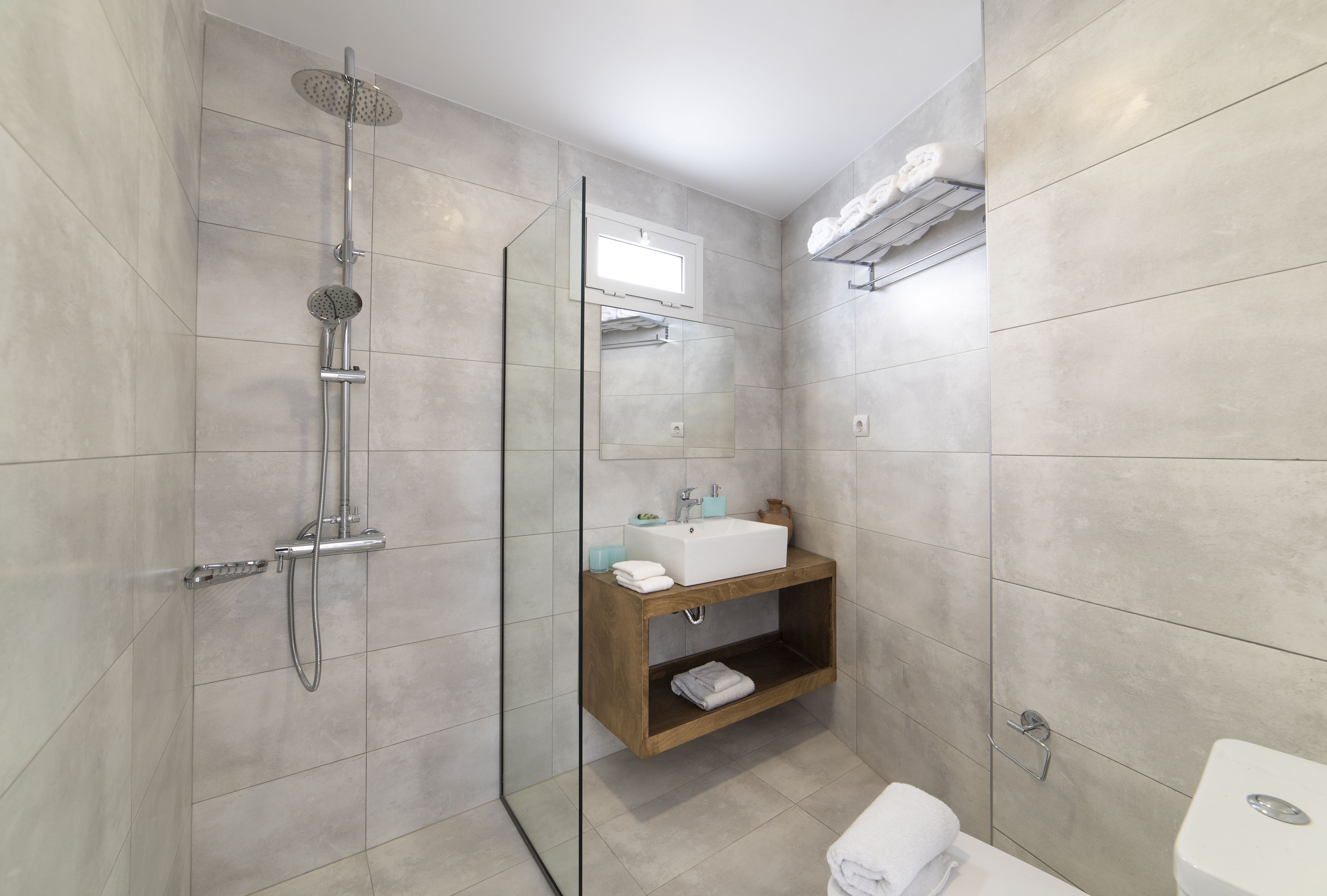 A modern bathroom with a glass-enclosed shower, a wooden vanity with a sink, and a toilet.