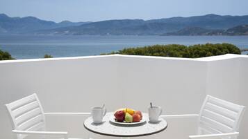 Un balcon avec une table dressée pour deux personnes, agrémentée d’un panier de fruits et de deux tasses.