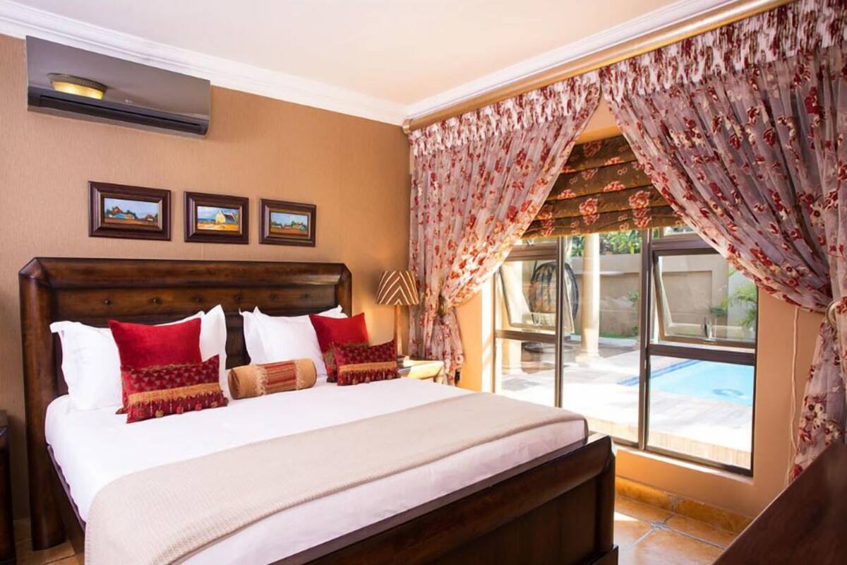Un dormitorio amplio con una cama grande, vista a una piscina y un ventilador de techo.
