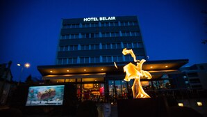 Un hôtel appelé HOTEL BELAIR, doté d’une façade moderne et d’une enseigne lumineuse.
