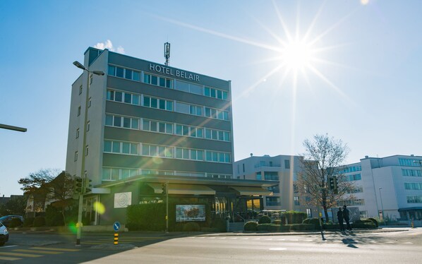 Un immeuble abritant un hôtel à plusieurs étages, sur lequel on peut lire l’inscription « HÔTEL BELAIR ».