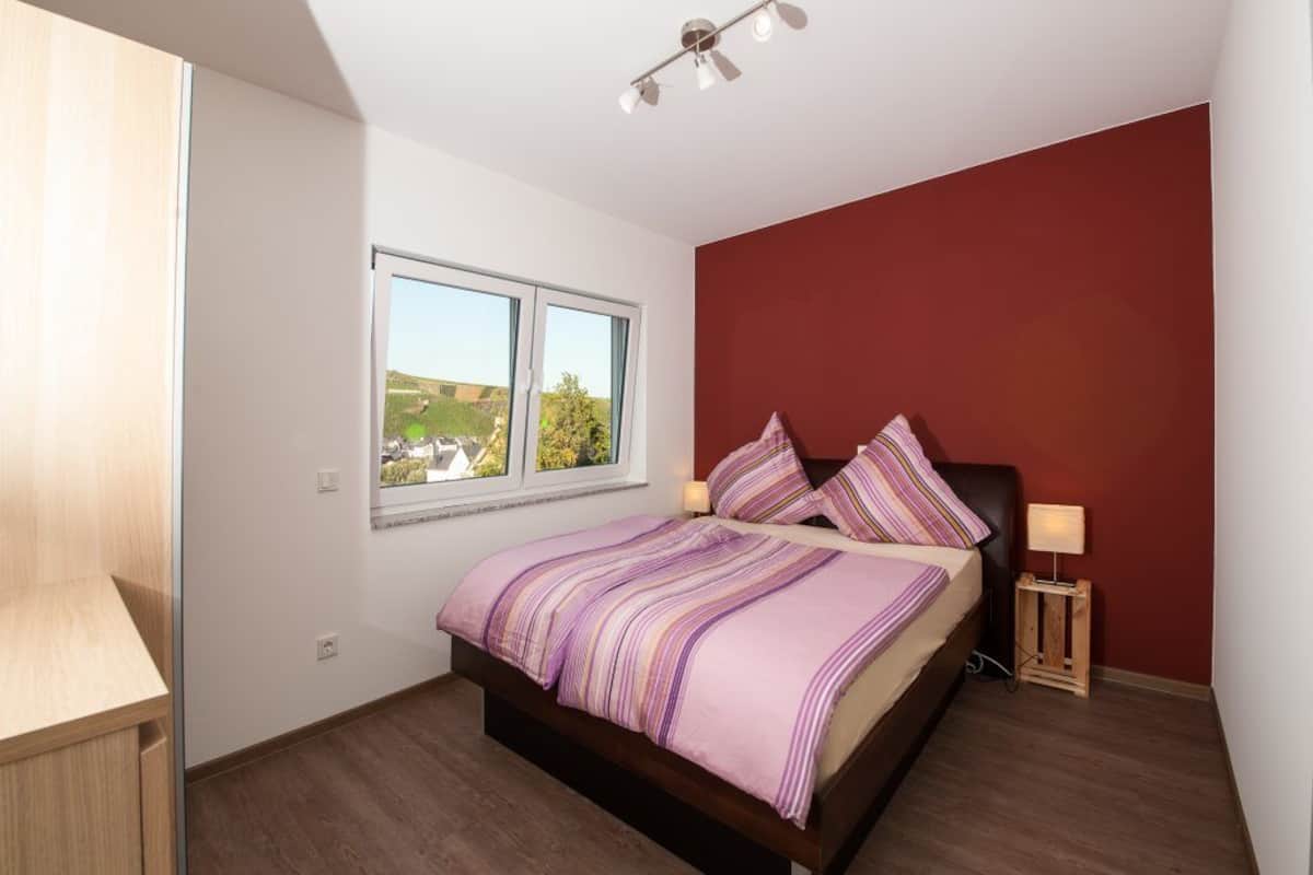 Quarto com cama, janela, mesa de cabeceira e abajur.