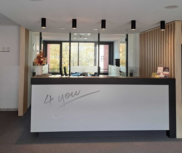 A reception desk with a large sign that reads "4 you" in the center. - Hotel4you (Dorfen)