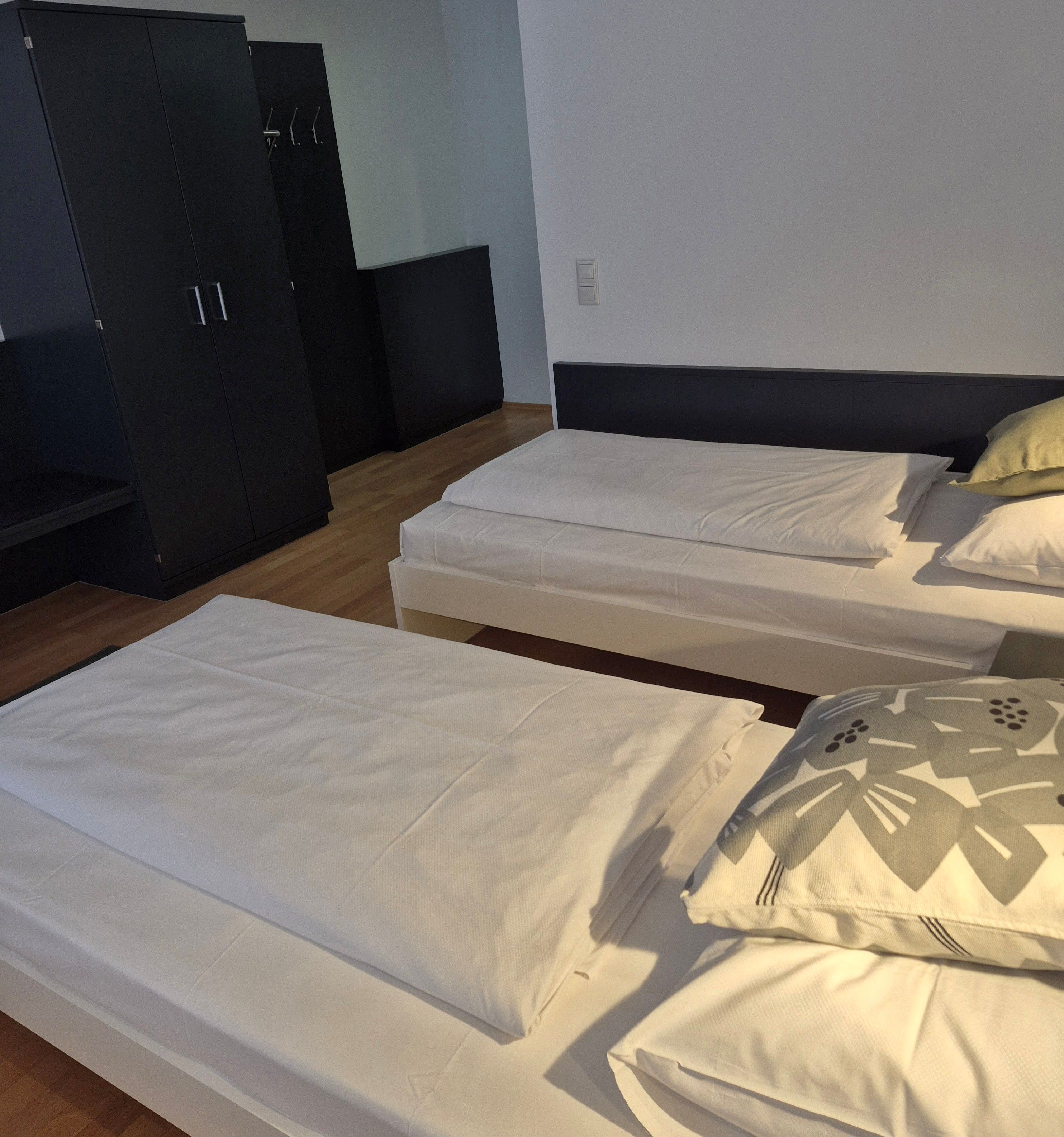 A room with two single beds, a wardrobe, and a small table.