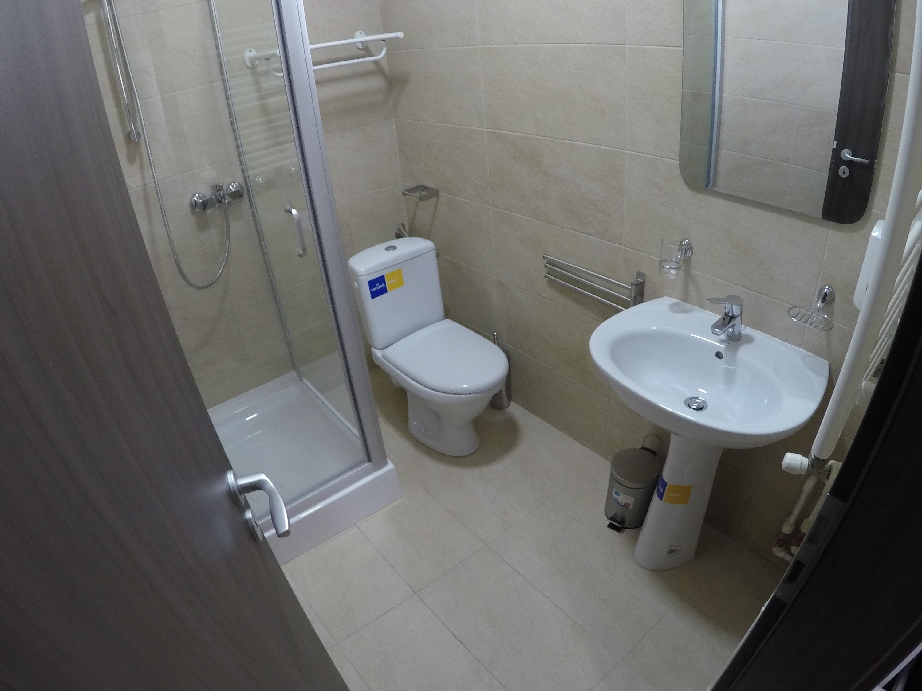 A bathroom with a glass shower enclosure, a toilet, and a sink.
