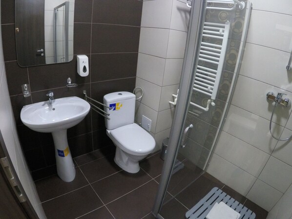 A bathroom with a white sink, toilet, and glass shower enclosure. - HB Brilliant (Brasov)