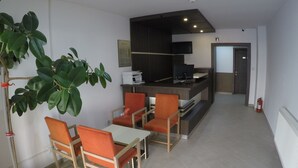 Una cocina moderna con estufa integrada y un comedor con sillas color naranja y una mesa.