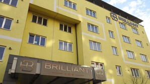 Un edificio amarillo de varios pisos con la señalización "BRILLIANT" y "HR BRILLIANT".