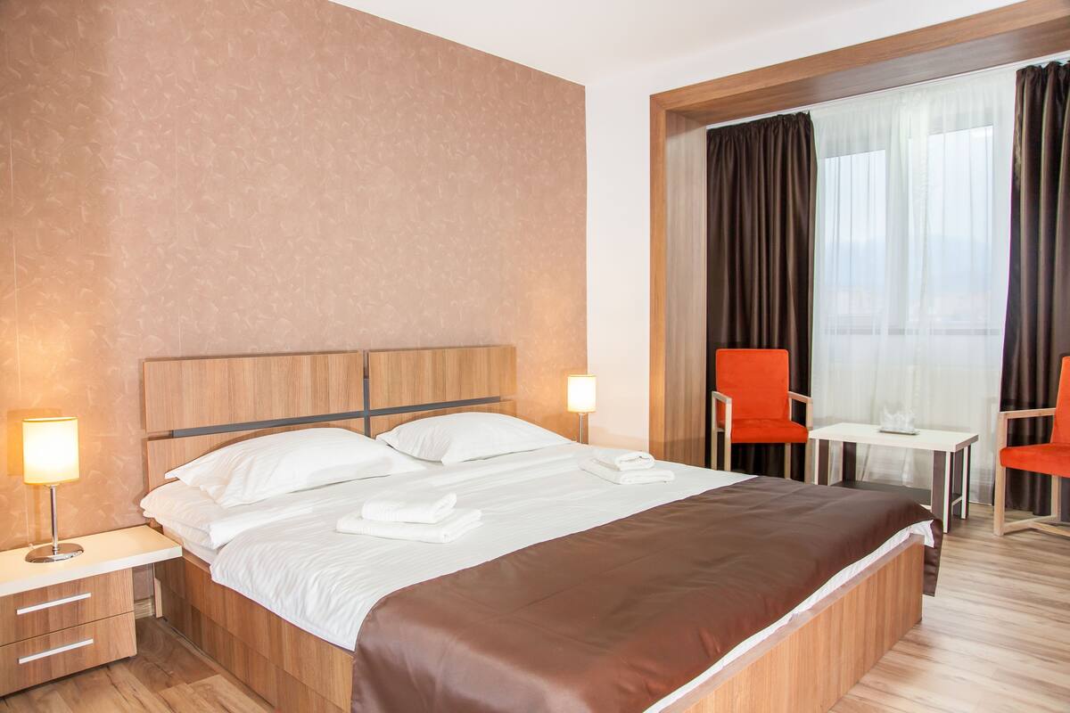 Una habitación de hotel con cama, mesitas de noche, un escritorio y una silla.