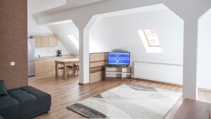 Un loft moderno con cocina, comedor y sala de estar con un televisor grande.