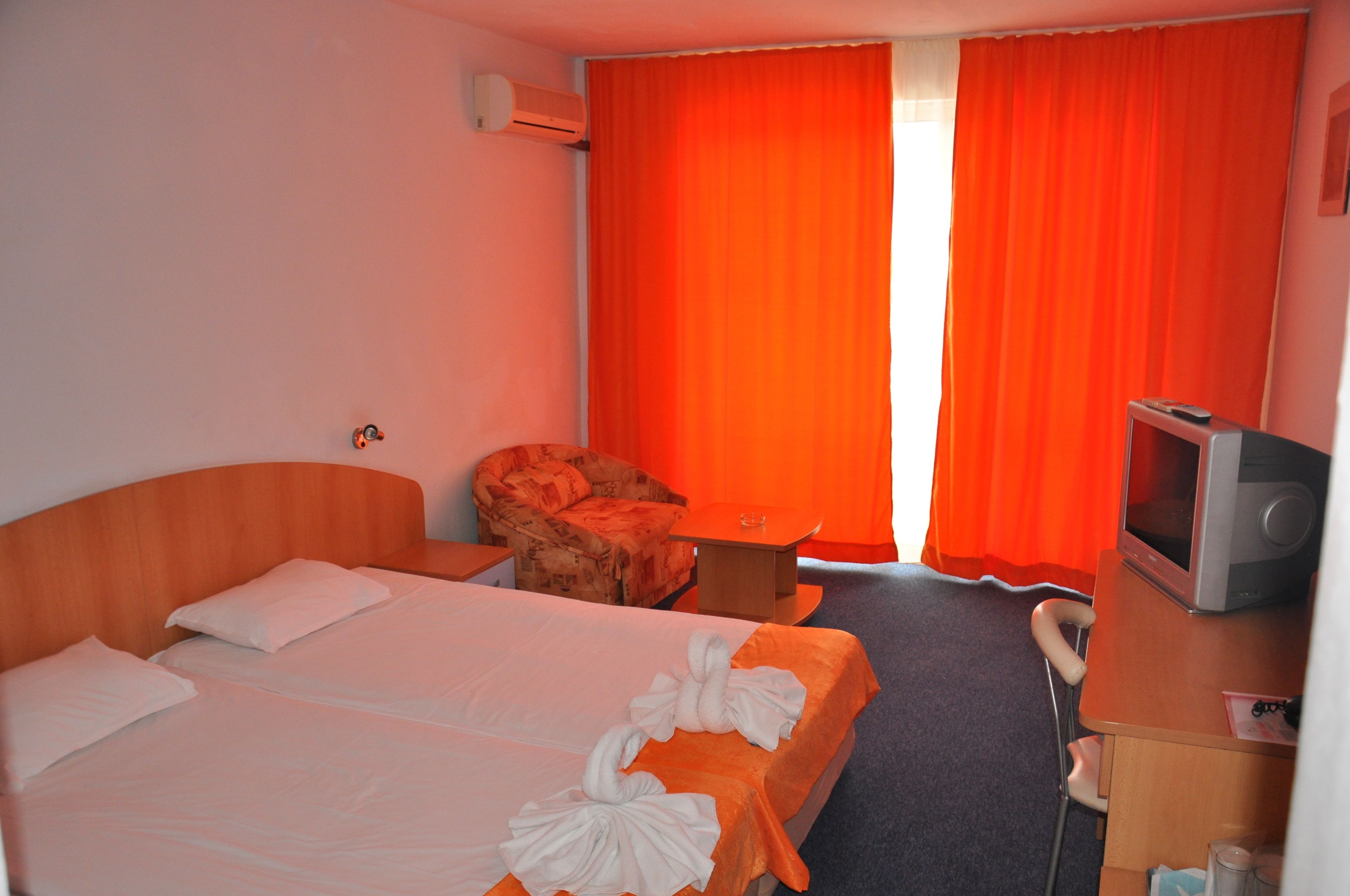 A hotel room with two beds, a sofa, a small table, a TV, and a chair.